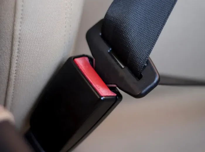 Close-up of a seat belt buckle receiver with its red release button beside the fastened belt.